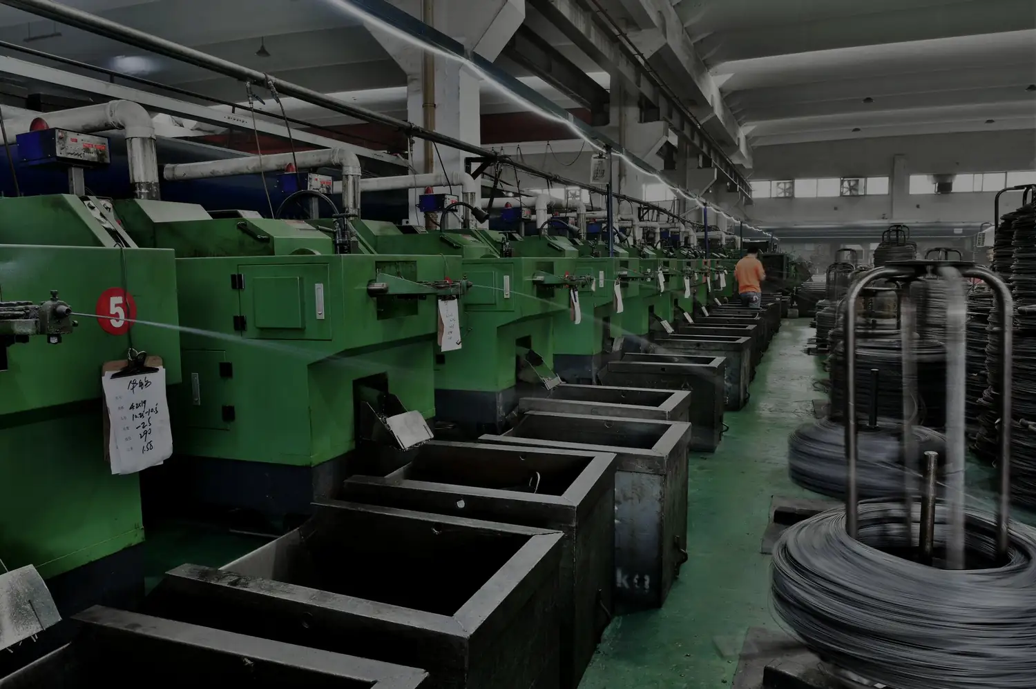 Row of multi-station cold-heading machines forming screw blanks from steel wire