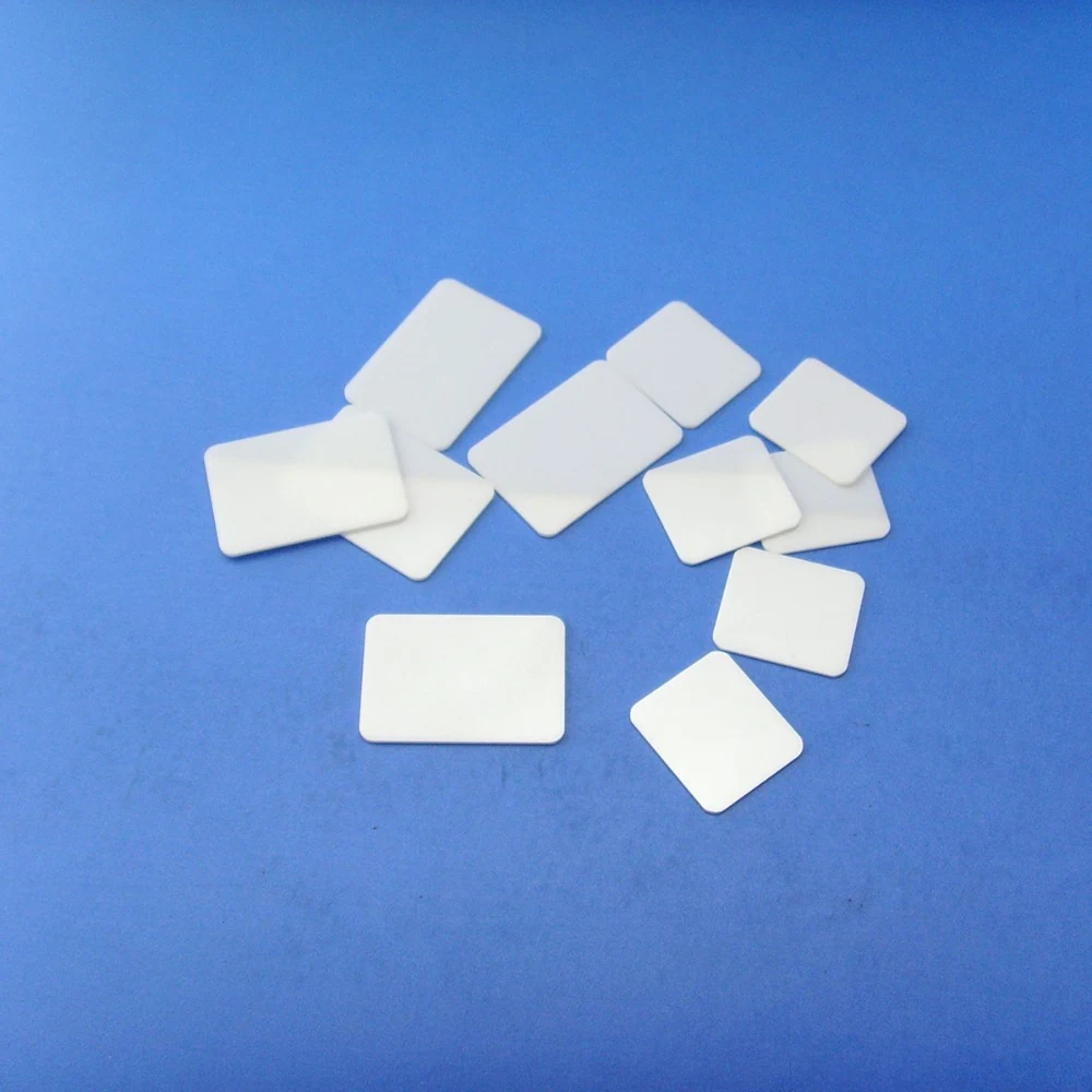 Thin white alumina ceramic substrate plates stacked on a blue background