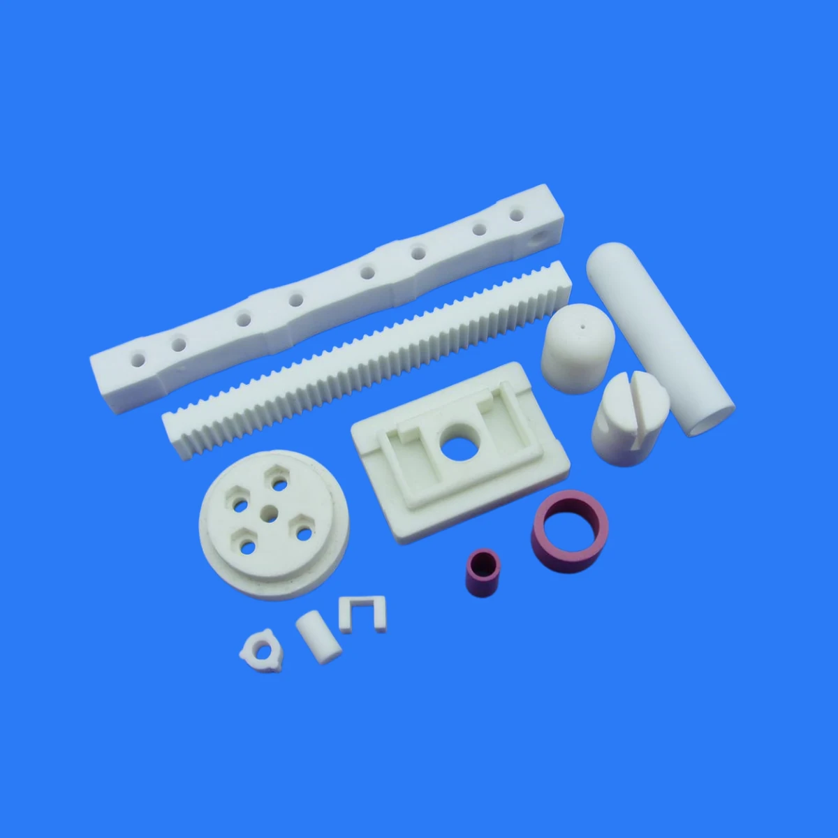 White zirconia ceramic rods bars and machined components on a blue background
