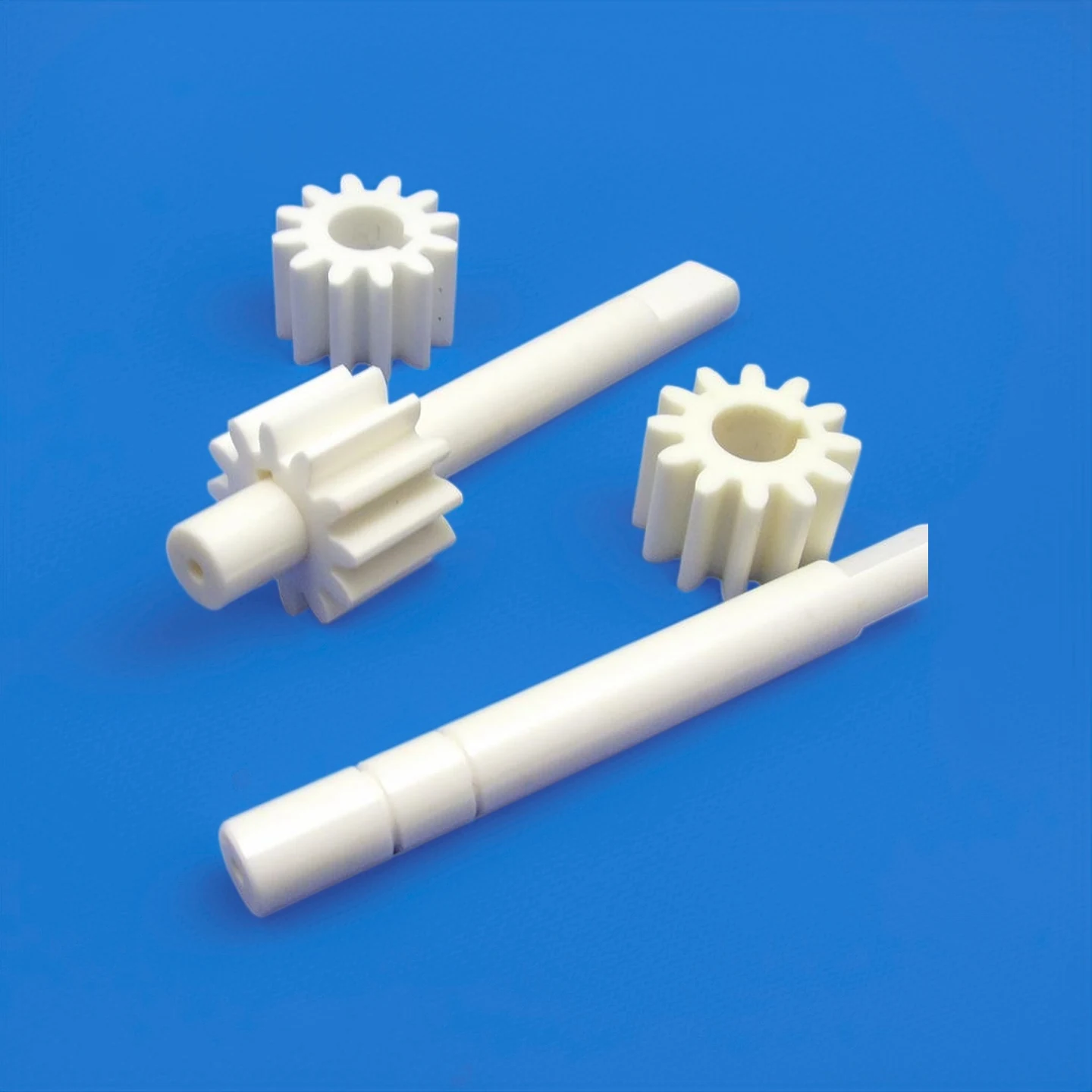 Machined ceramic gears rods and shafts on a blue background