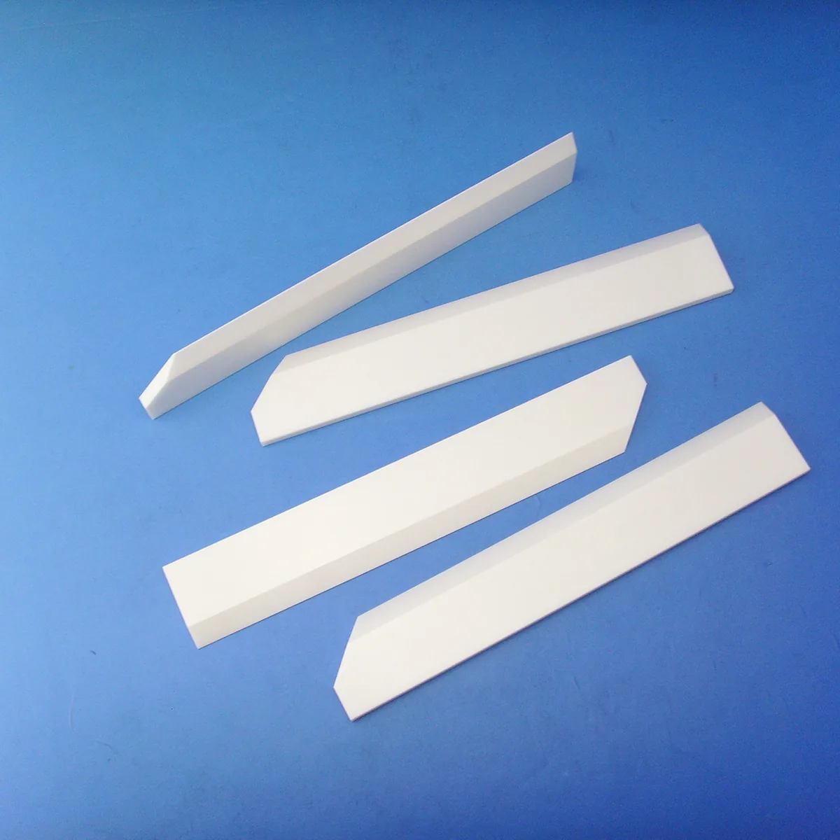 White precision zirconia ceramic blades with ground cutting edges on a blue background