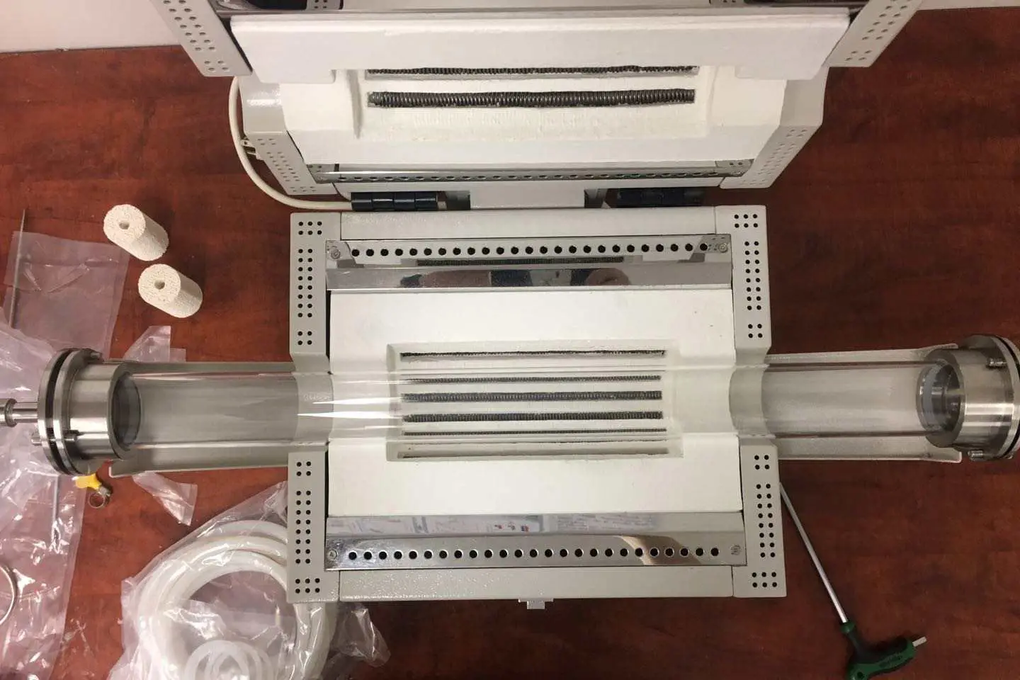 Split tube furnace opened to show the heating elements and quartz process tube